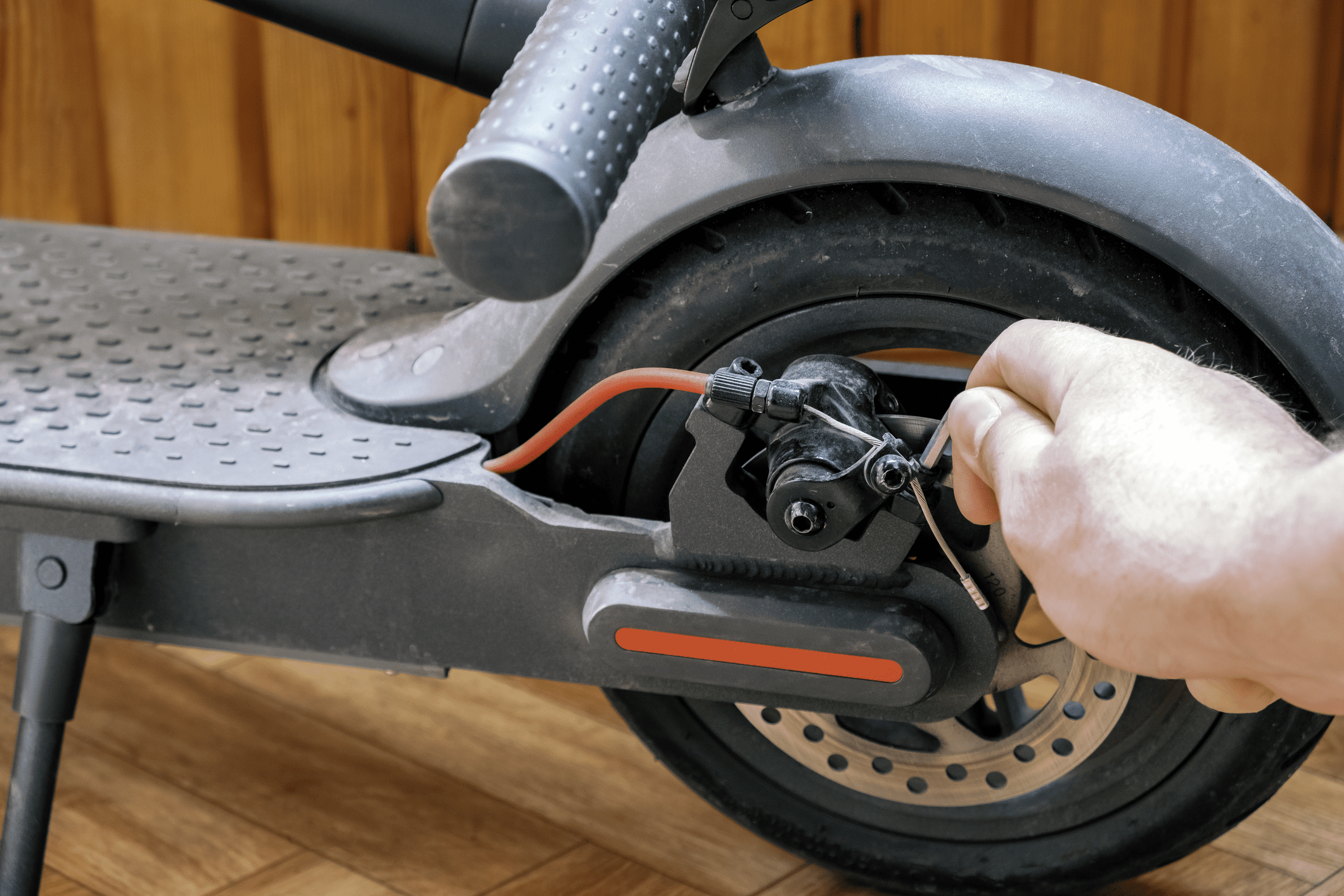 A person inspecting the brakes of an electric scooter